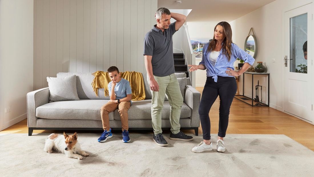A family of three is gathered in their living room with their puppy.
