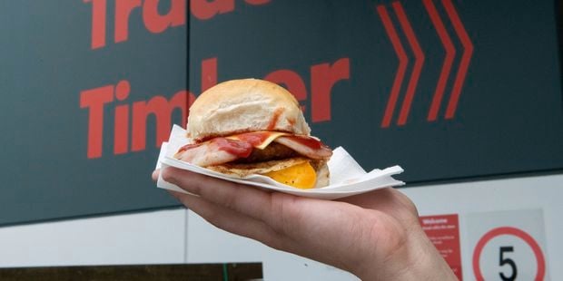 A person holding up a bacon and egg roll.