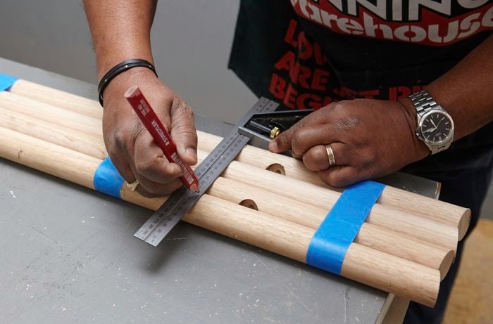 Several lengths of wide dowel being marked for cutting