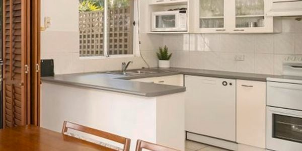 Kitchen with white cabinets and grey benchtops.