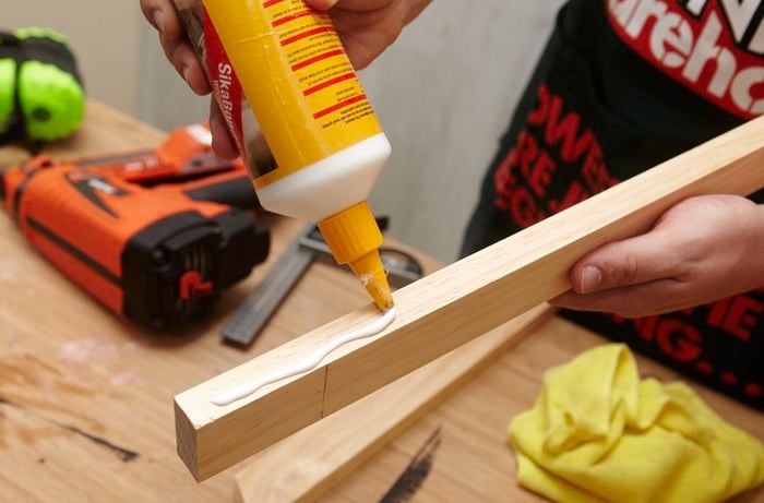 Person putting glue on piece of wood.
