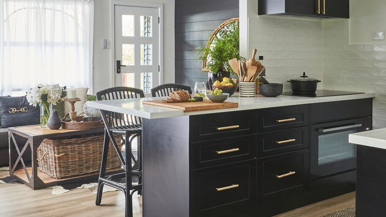 Modern monochrome kitchen with black cabinetry with gold coloured handles and timber look floorboards