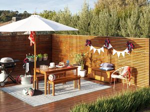 Decorated outdoor entertaining space with barbecue, dining table, bunting and sporting accessories.