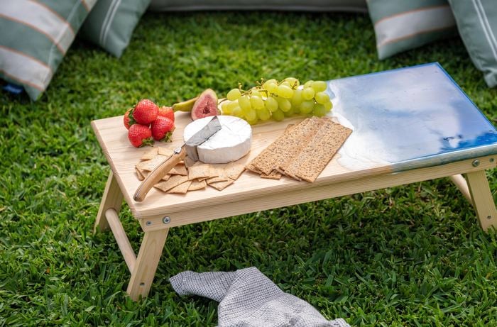 A small picnic table with some fruits and a block of cheese.