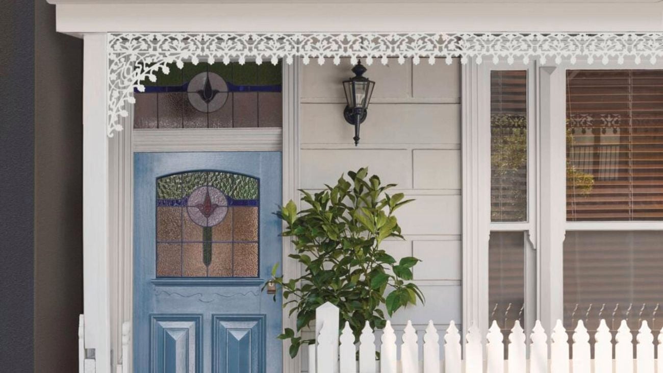 Front of white cottage with white picket fence and blue painted door