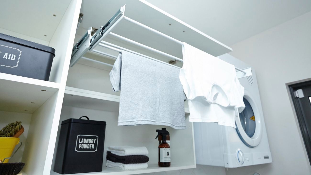 A drying cupboard with two tee shirts hanging on the drying rack.