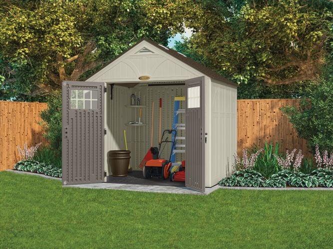 Backyard garden shed containing a mower and garden tools