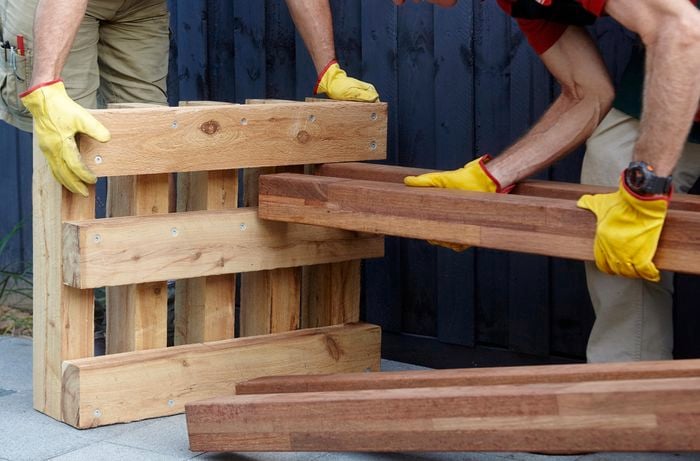 Timber lengths being inserted into one end of a wooden outdoor day bed