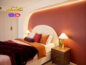 Bedroom with patterned wallpaper, pink bedding, and bedside lamps.