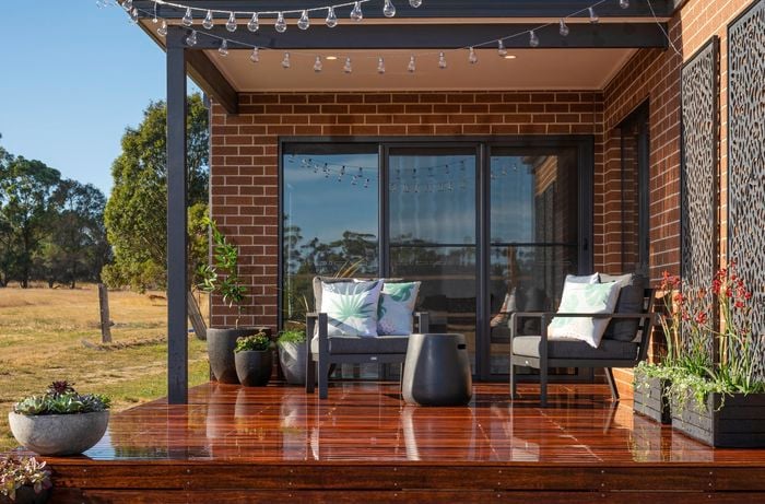 Wooden decking outside a house with chairs, plants and 2 x garden panels.