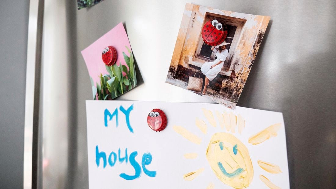 Completed ladybug fridge magnets holding up pictures and child paintings on a fridge