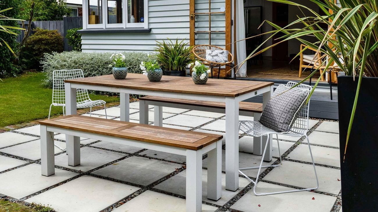 A table and chairs in a backyard on a paved area