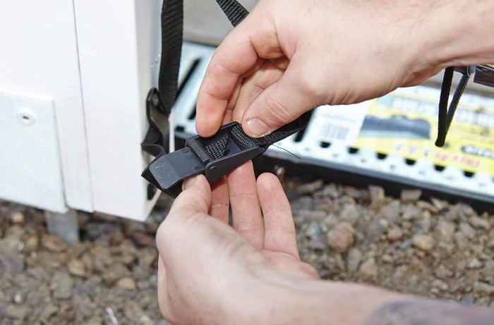 A person adjusting an anchor belt with a plastic clip