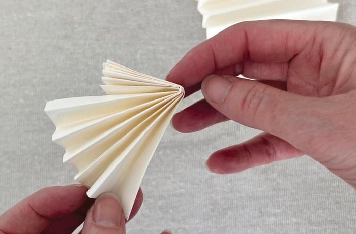 Hands hold pieces of pleated paper