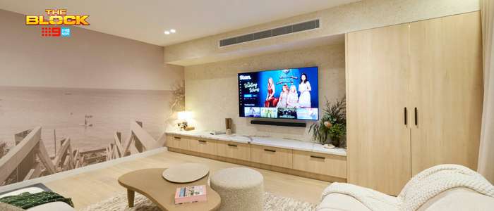 Contemporary living room featuring curved neutral sofas, a timber entertainment unit, wall-mounted TV and built-in timber cabinetry.