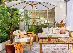 An outdoor styled space with an umbrella, outdoor setting and timber table.