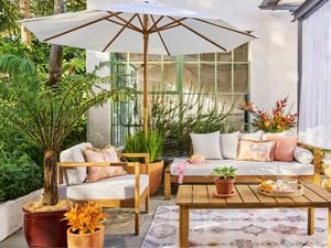 An outdoor styled space with an umbrella, outdoor setting and timber table.
