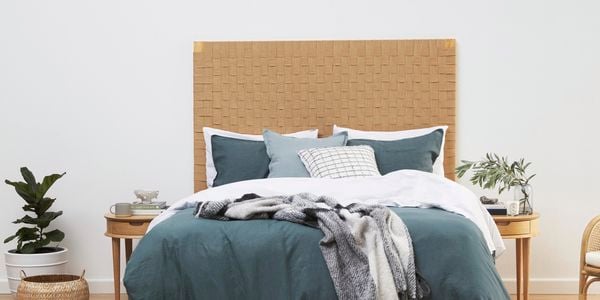 bed with cool tone sheets and pillows and jute bedhead