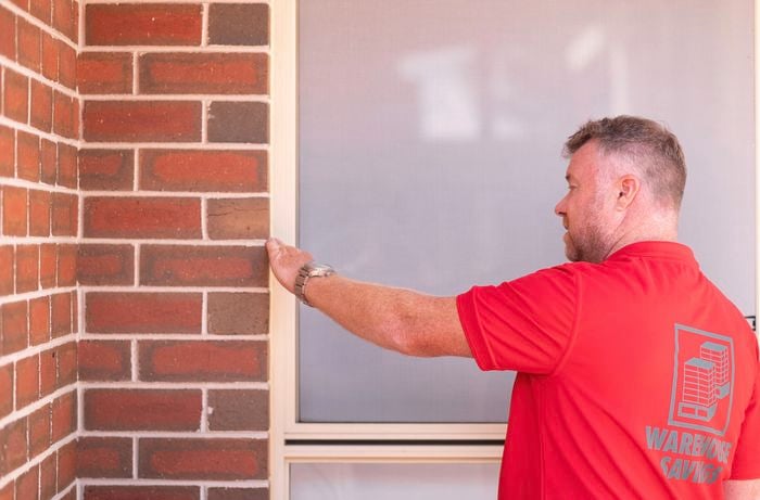 A Bunnings team member is inspecting the window frame.