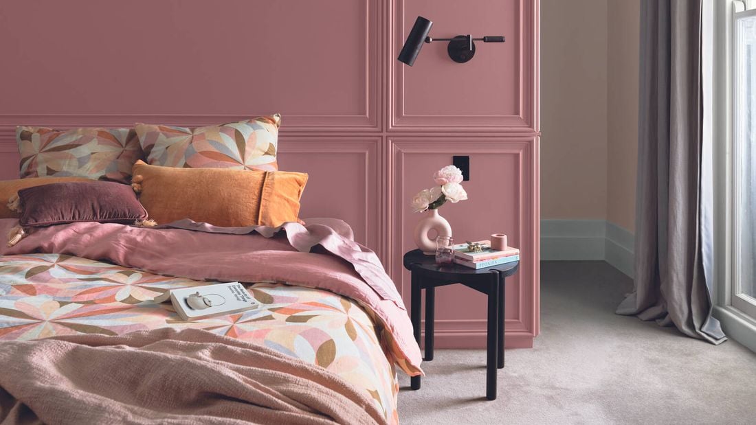 luxe bedroom with soft pink walls and timber side table