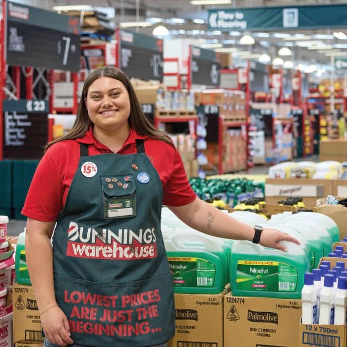 A female Bunnings Team Member in a Bunnings store filled with products in boxes and on dexion.