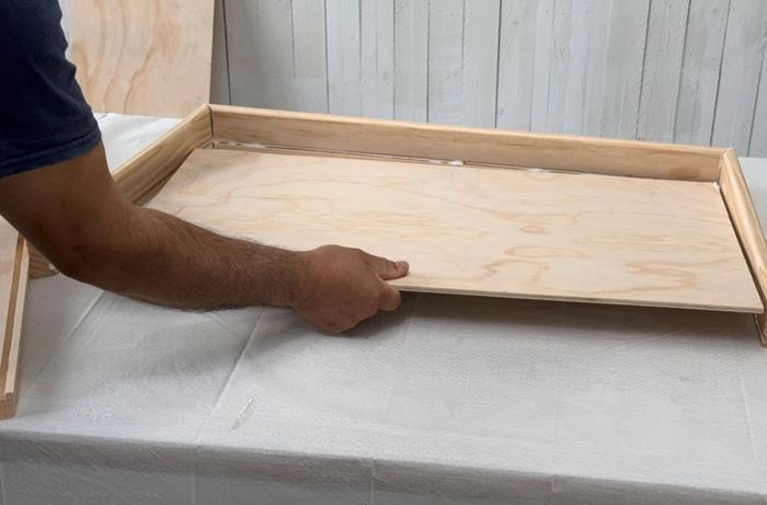 Drawer base being inserted into rebates in drawer frame.