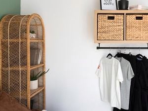 Clothes rail underneath basket with clothes on hangers.