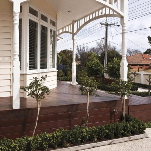 CWhite weatherboard heritage house with wrapped deep coloured decking
