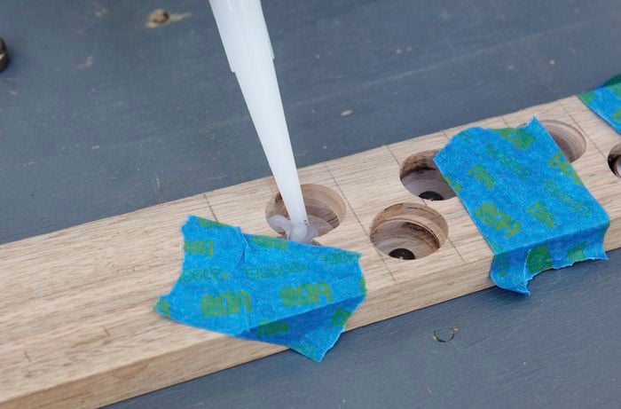 Silicon being applied into holes in a piece of timber