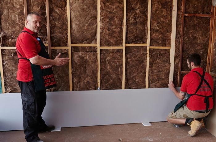 Plasterboard being hung on a bare stud wall by two Bunnings team members