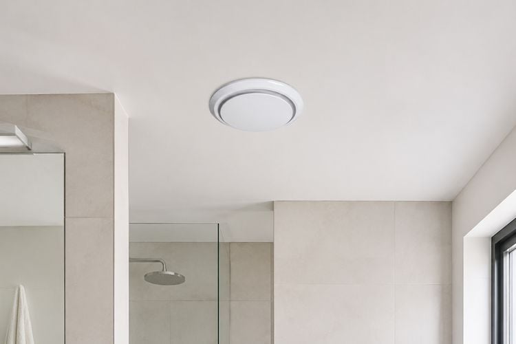 Round white exhaust fan installed flush in a bathroom ceiling.