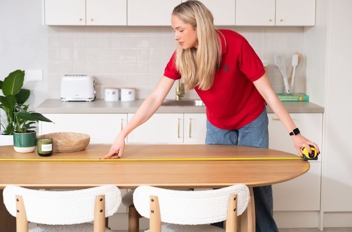 A Bunnings Team Member is measuring the centre of a dining table to plan pendant light placement