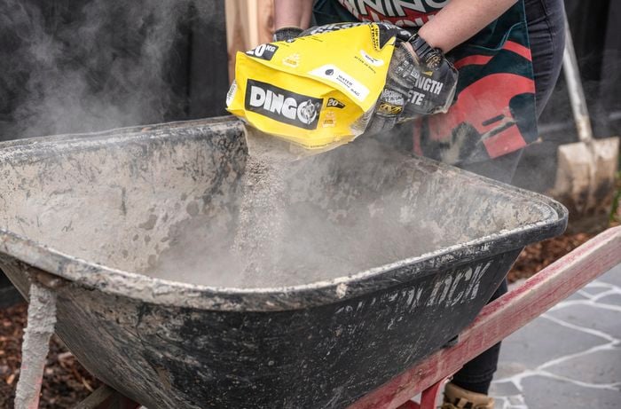 person mixing concrete using a wheelbarrow