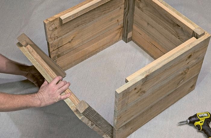 Hands positioning a timber panel make a wooden box.
