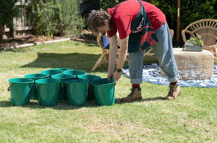 Person lining up green buckets into a triangle.