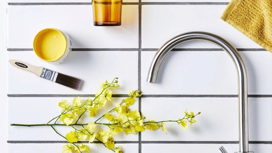 White subway tiles with a stainless steel tap, paint and foliage.