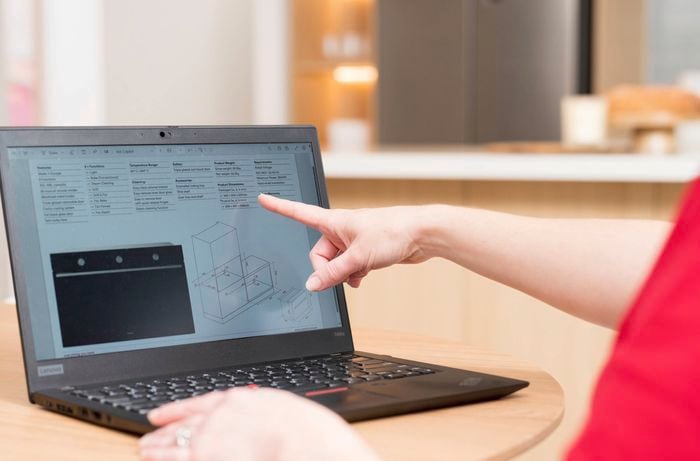A person points to appliance specifications and dimensions, aiding precise kitchen planning.
