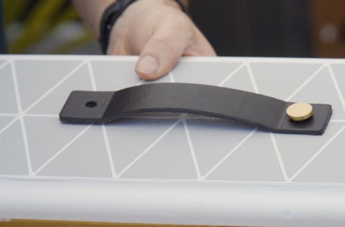 Strap type handle attached to the front of a drawer
