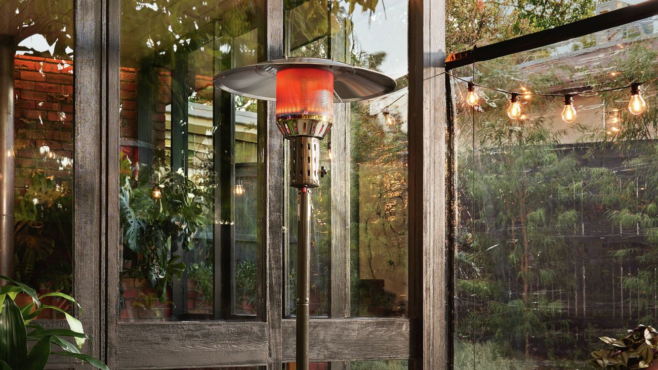 Outdoor patio with an outdoor heater, surrounded by festoon lights and glass doors.