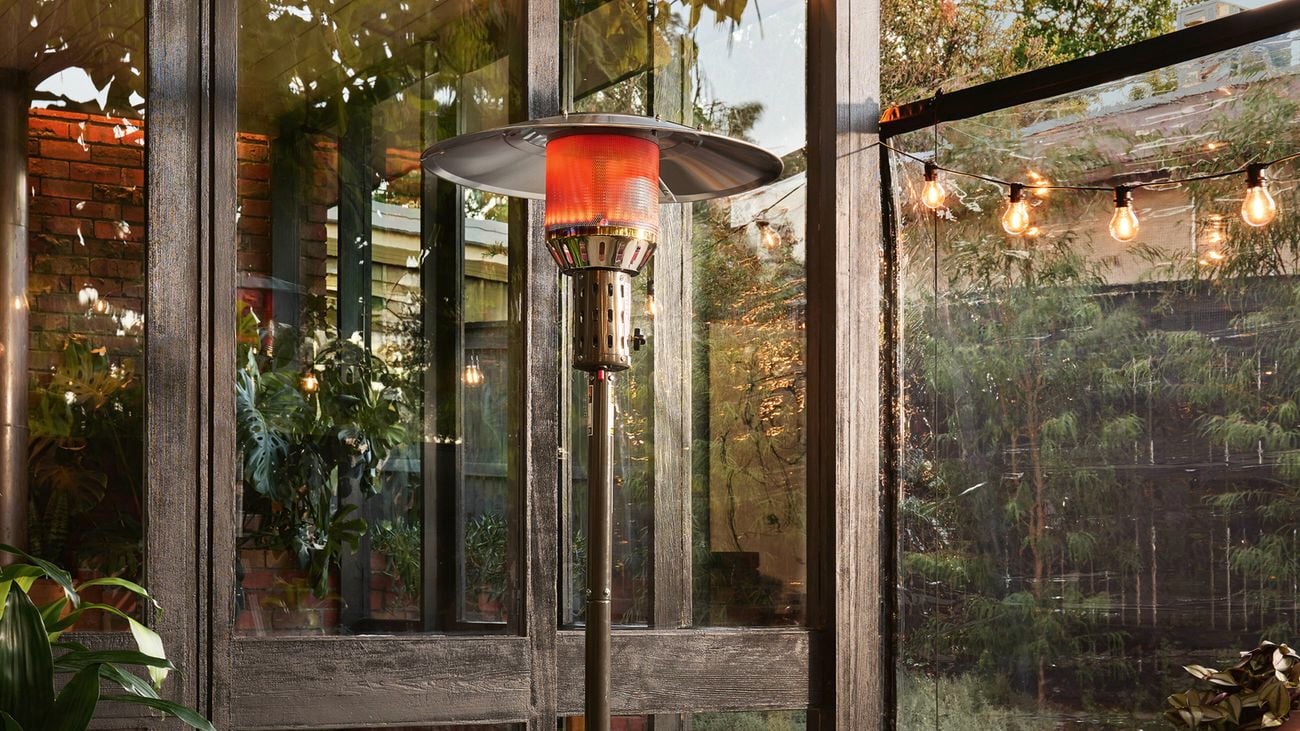 Outdoor patio with an outdoor heater, surrounded by festoon lights and glass doors.