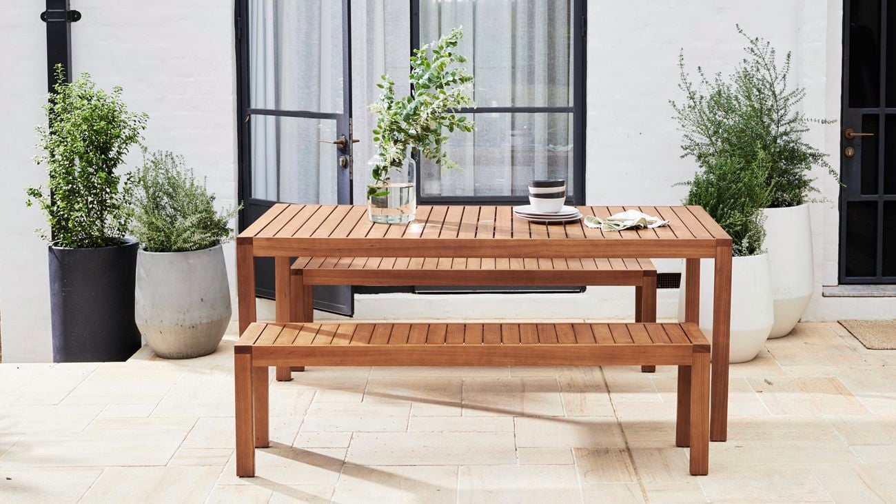 Timber outdoor dining table in a paved courtyard