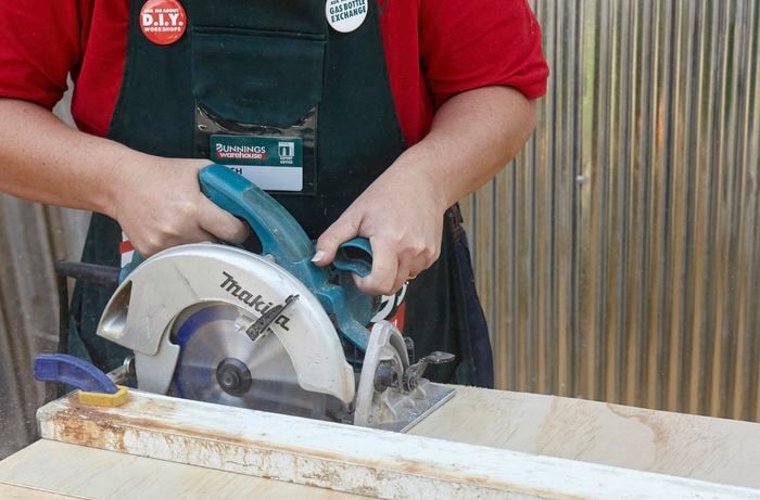 A person cutting plywood with a circular saw