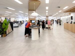Wide view of a spacious tile showroom with customer service areas, product displays, and people exploring the space