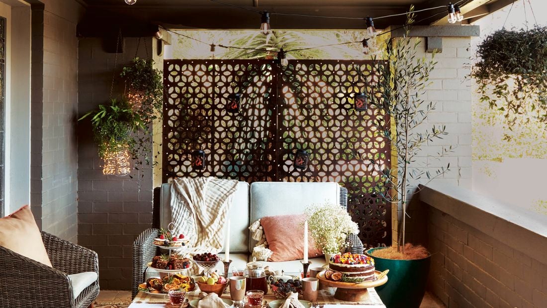 Small outdoor patio showcasing privacy screen, outdoor lounge and decorative lighting.