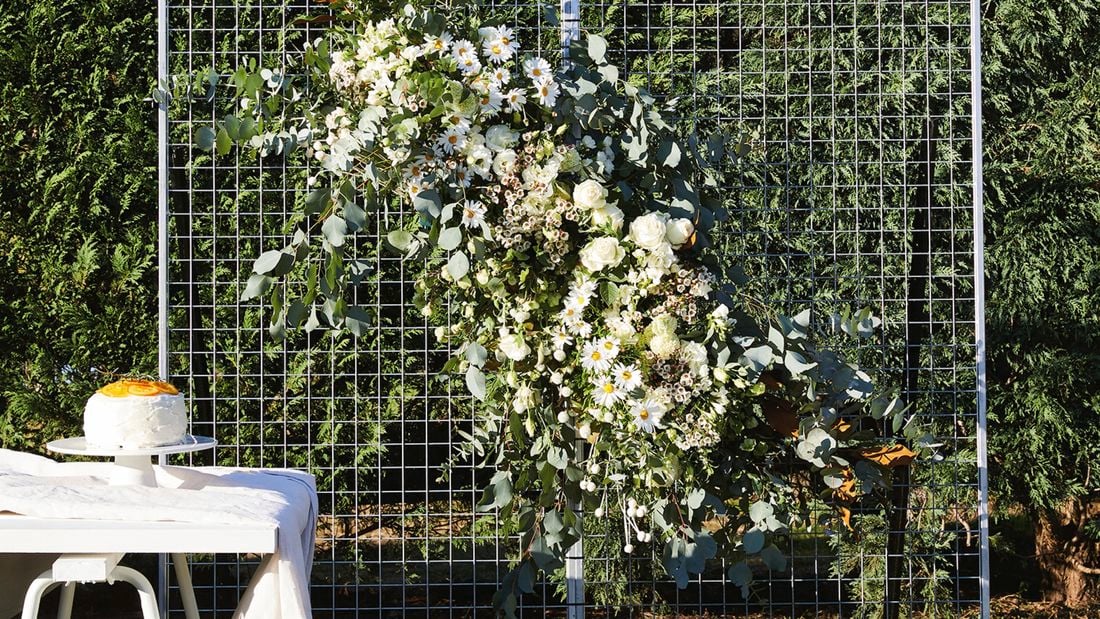 A floral wall made from wire panels adorned with white flowers.
