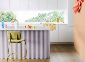 A bright modern kitchen with white wall cabinetry, curved benchtop and wide window.