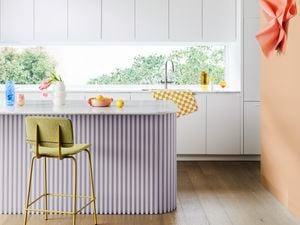 A bright modern kitchen with white wall cabinetry, curved benchtop and wide window.