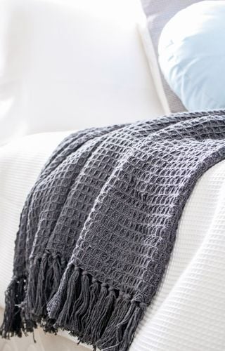 Close up of a mauve throw rug on a white bedspread