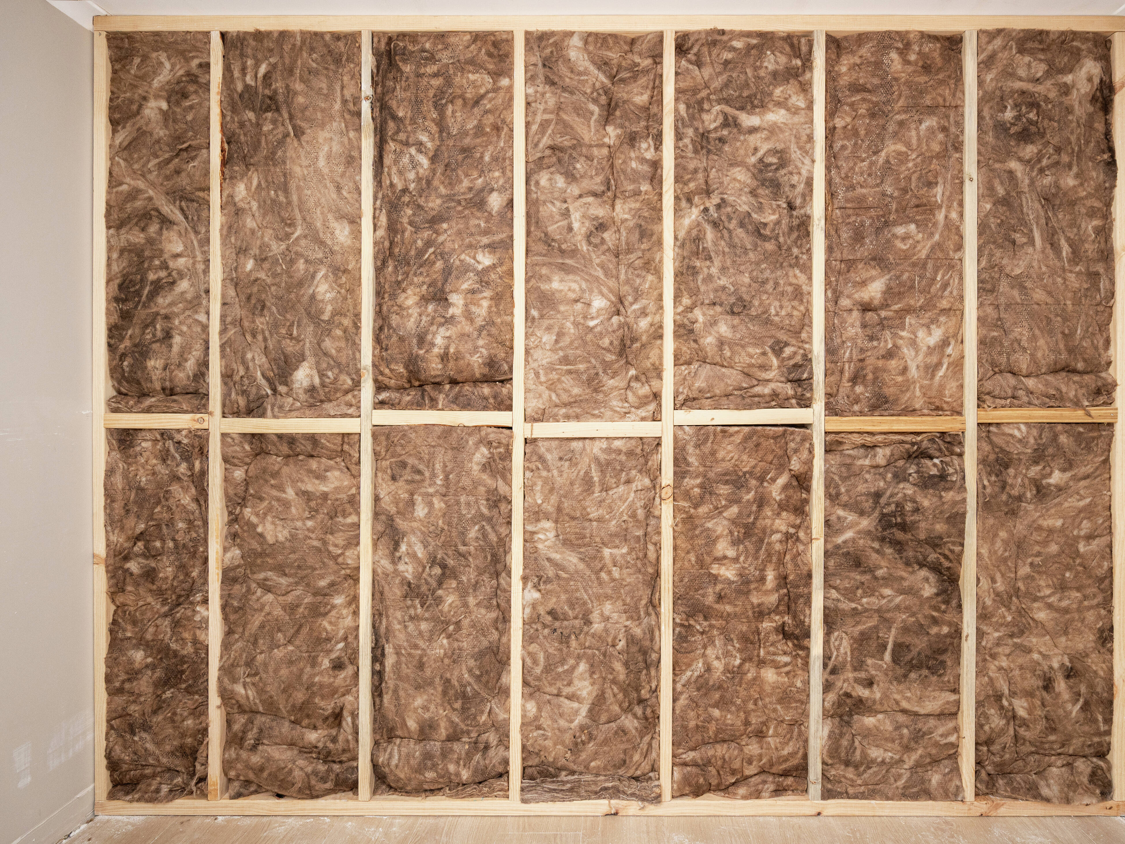 worker installing moisture-resistant drywall over insulated kitchen wall studs