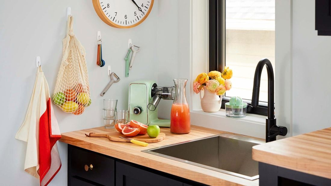 Utensils and bag hanging from a wall in a kitchen using hooks.